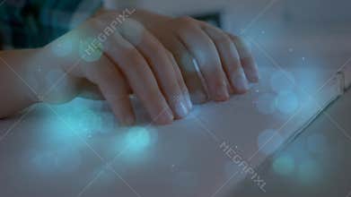 Blue spots of light against close up of hands reading a book in braille