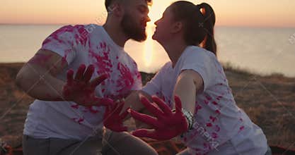 Gender party on a hill. The couple is waving pink hands and kisses.