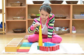 Little girl hand building tower made of montessori educational