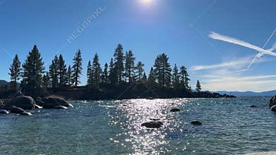 Wide scenic view of Sand Harbor beach cove with emerald water and pine forest background