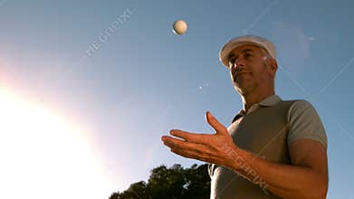 Golfer throwing and catching golf ball on the course