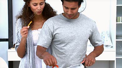 Woman eating while her husband is cooking vegetables