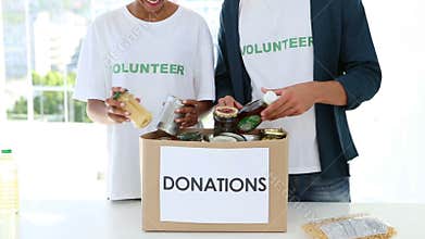 Happy volunteer team packing a food donation box