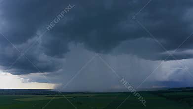 Broad Storm Front Over Expansive Green Farmland with Distant Rain Curtain