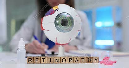 Text Retinopathy on wood cubes pills drops and eye model on desk