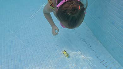 A little girl dives underwater for a toy