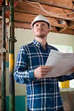 Architect Inside House Being Renovated Studying Plans
