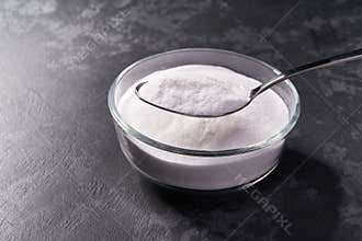 Close-up of baking soda in a metal spoon on a black background