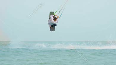Businessman rides a kite in the tropical ocean and performs tricks Slow motion