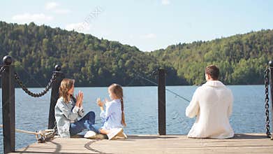 Happy family with daughter fishing in pond in fall