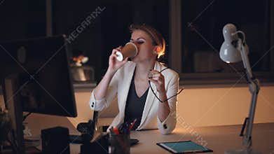 Pretty young woman secretary is working on computer late at night then taking off glasses and rubbing tired eyes and