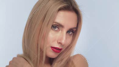 Beautiful blond girl with long hair, classic make-up and red lips posing in the studio. Beauty face.