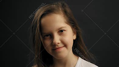 Portrait of little young girl looking at the camera. Black background in the studio. 4K slow motion shot