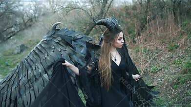 Mysterious lady with pale fair skin in long flowing dress with lace sleeves posing for camera, girl with large black