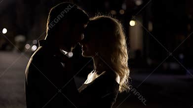 Silhouettes of husband and wife nuzzling, romantic date, love relationship