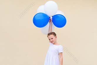 Happy little girl with blue and white balloons.