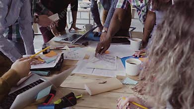 Top view of young team working on architectural project. Group of mixed race people standing near table and discussing.