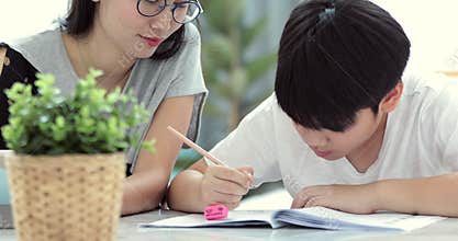 Asian Mom is helping her son to do homework