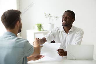 African employer handshaking new hire caucasian employee holding