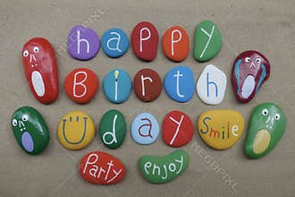 Happy Birthday with a smile and multicolored stones over beach sand