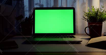 Laptop with green screen. Dark office. Dolly out. Perfect to put your own image or video.Green screen of technology being used. Ch
