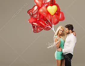 Happy loving couple on grey background with heart balloons