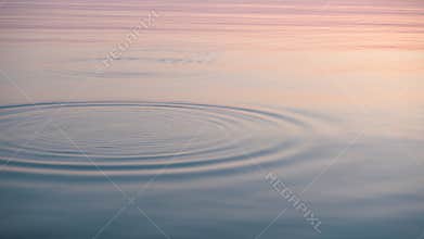 Stone skipping on beautiful calm water, majestic sunrise around.