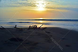 Beautiful long exposure photography of sunrise at sea shore with sea water coming over the sand
