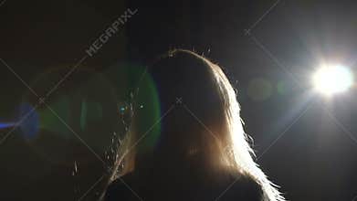 Silhouette of blond girl with flying hair in the wind in a long corridor in dark