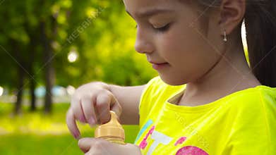 Little girl blowing soap bubbles in park. Closeup video