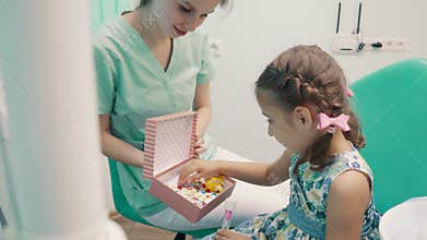 Children`s dentist entertains little girl