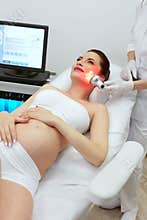 Cosmetology. Pregnant Woman Doing Red Light Therapy At Clinic