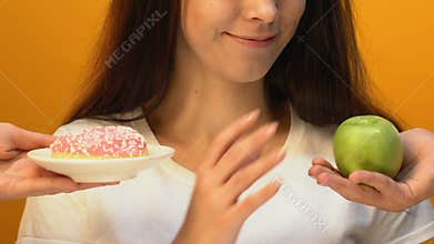 Cheerful lady choosing green apple instead of sweet donut, weight loss, close up