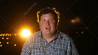 Man surprised by something by shakes his head and opens his mouth at night outdoor