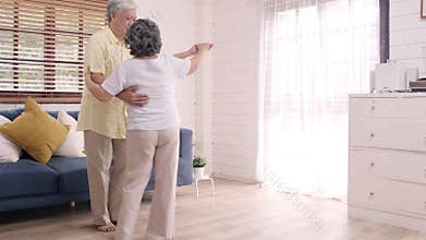 Asian elderly couple dancing together while listen to music in living room at home.