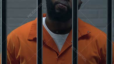 Confident African-American head of mafia standing in prison cell, criminal