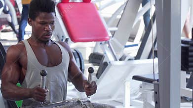 Ripped young African man working out on low row cable gym machine