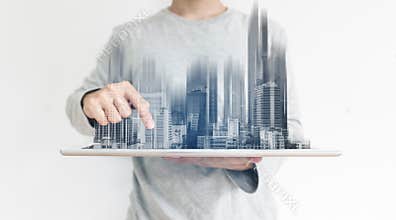 A man using digital tablet, and modern buildings hologram. Real estate business and building technology concept