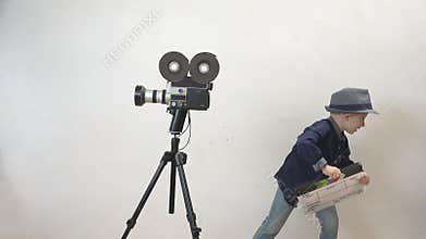 Funny child holding a clapboard, little director having fun, old camera, action