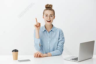 I have great idea. Smart attractive female office manager in stylish glasses, sitting near laptop and smartphone