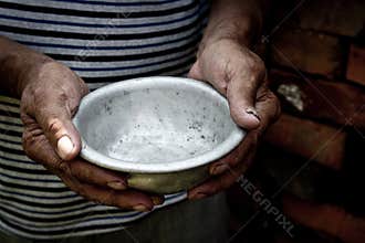 The poor old man`s hands hold an empty bowl. The concept of hunger or poverty. Selective focus. Poverty in retirement.Homeless. Al