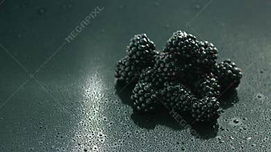 Pile of shiny blackberries on wet surface