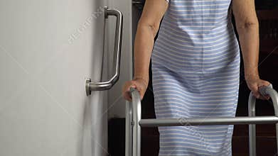 Elderly woman holding on handrail for safety walk.