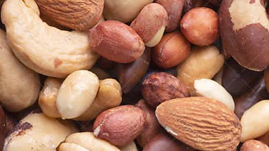 Closeup top view of mixed nuts over a wooden background. Peanuts, brazilian nuts, cashew, baru and almonds