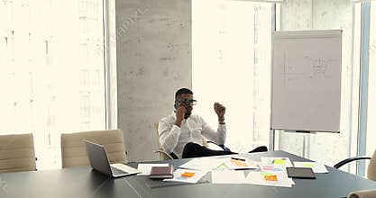 Serious African businessman talks on cellphone, checks time, makes appointment