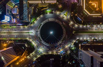 Top down overhead aerial view of moving car traffic at roundabout Vehicle road traffic around Selamat Datang monument in
