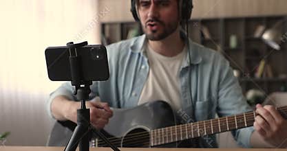 Artist playing a guitar recording music video on smartphone