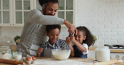 African father and children cooking together in kitchen