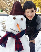 Young Boy with a Snowman That He Built