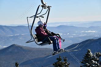 Chairlift with people at Stowe Ski Resort in Vermont, view to the Mansfield mountain slopes